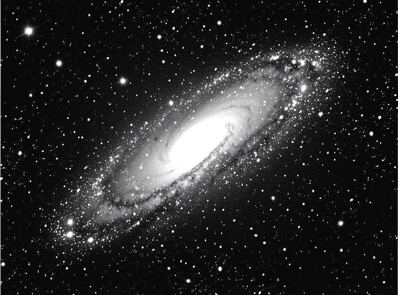 A luminance mask isolating the dark background of a galaxy image so noise reduction spares the stars