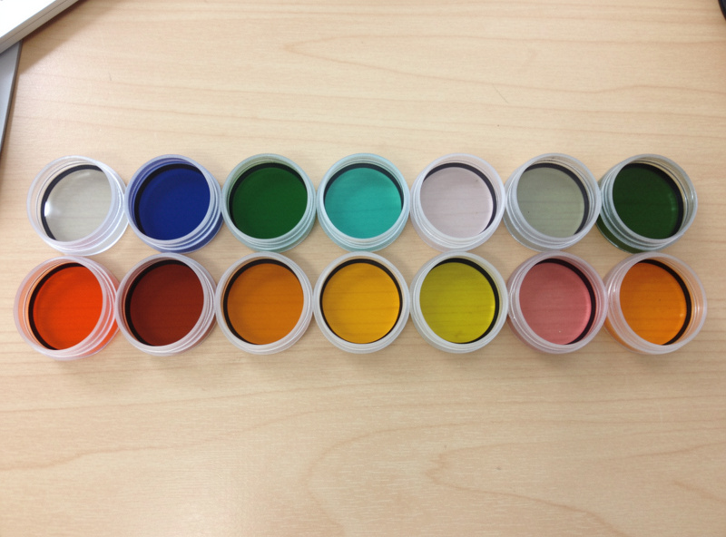 A row of telescope filters in their cases laid out for comparison on a desk