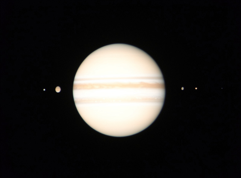 The four Galilean moons of Jupiter as bright points strung out beside the planet through a telescope