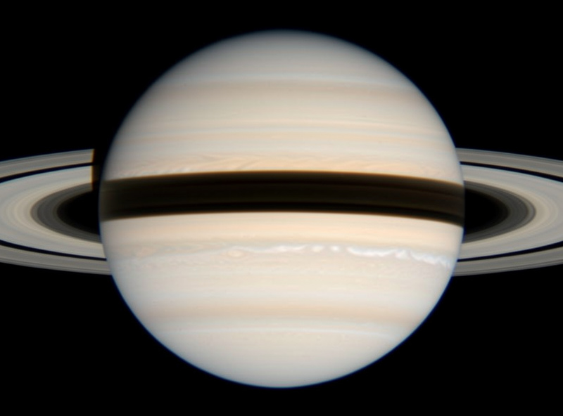 Telescope view of Saturn's rings showing the thin dark Cassini Division and the ring shadow on the planet